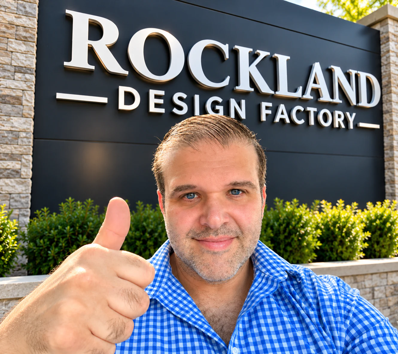 Man giving a thumbs-up in front of the Rockland Design Factory sign.