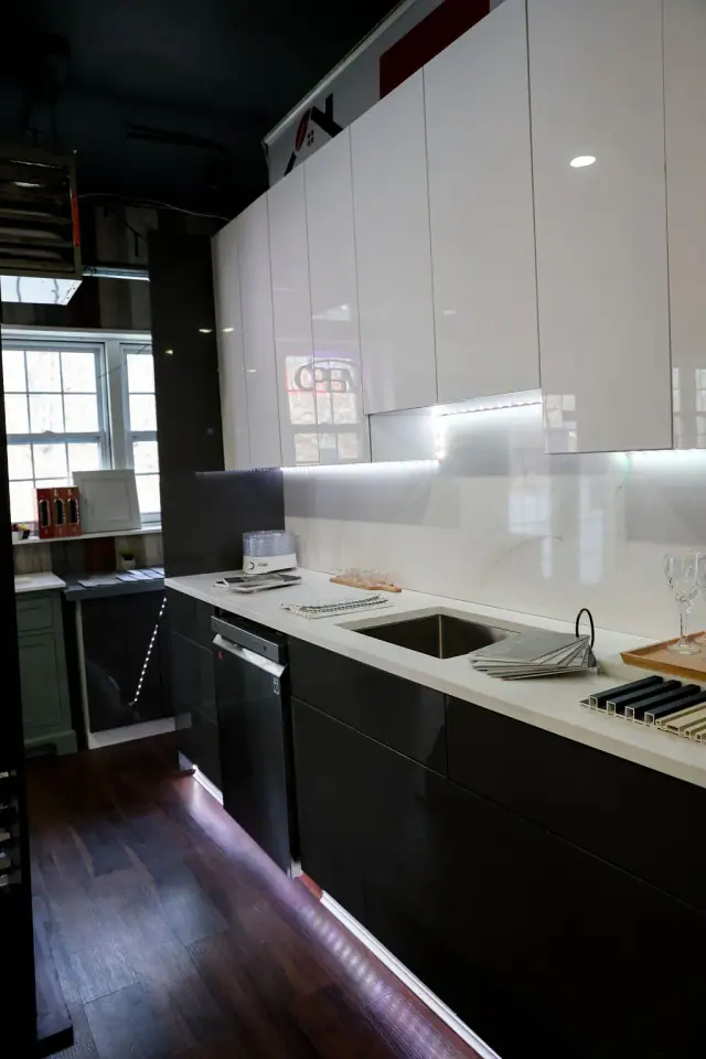 Gray sink display with illuminated backsplash and dark cabinets