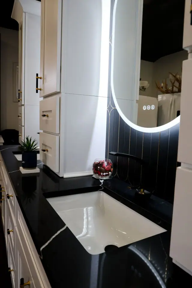 Dark vanity display with tall illuminated oval mirror