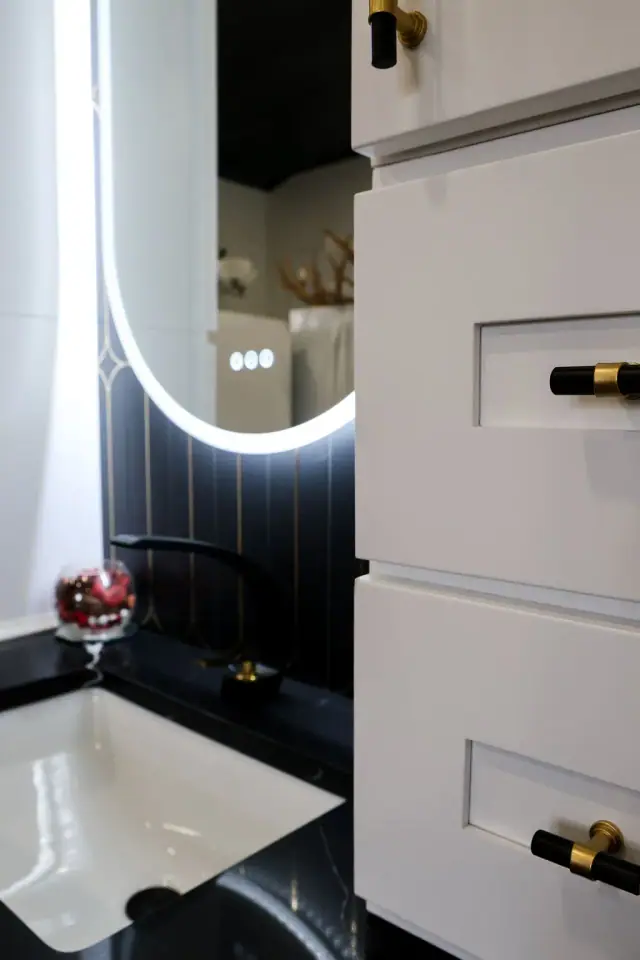 Dark vanity with illuminated mirror and white side cabinet