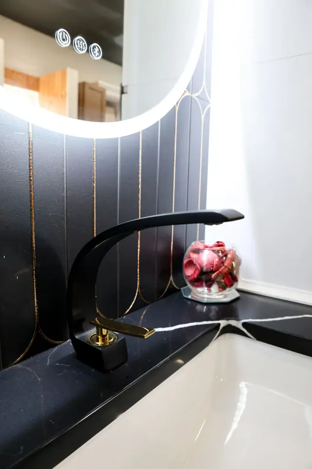 Black faucet and tile samples beside an illuminated shelf