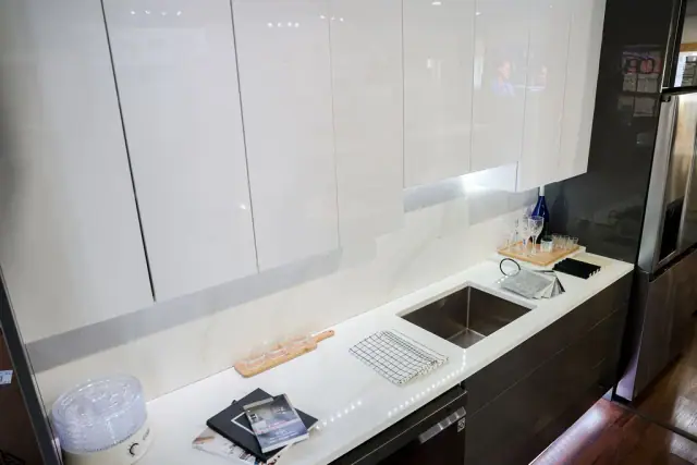 Gray sink run with under-cabinet light and stone backsplash