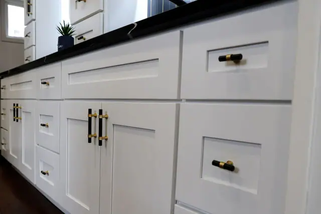 White cabinet drawers with black and brass hardware